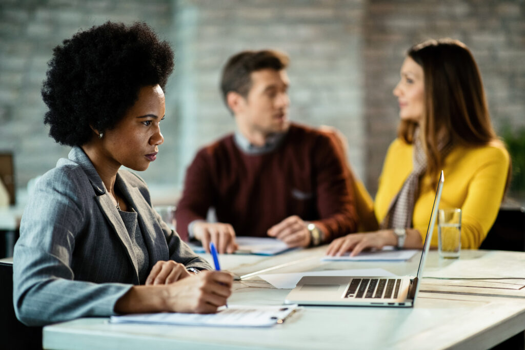 african american financial advisor taking notes while using computer on a meeting.